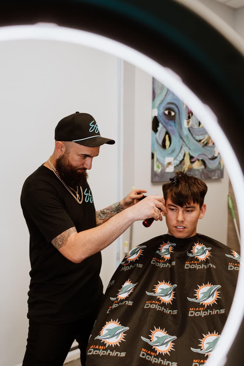 Chris Sacconi cutting a client under the ring light in the suite