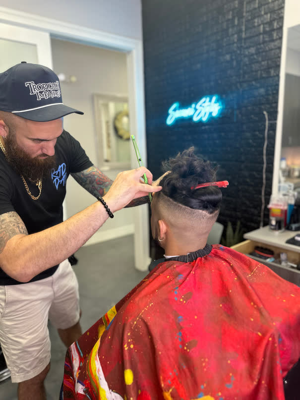 Chris shaping a fade with the neon sign behind him
