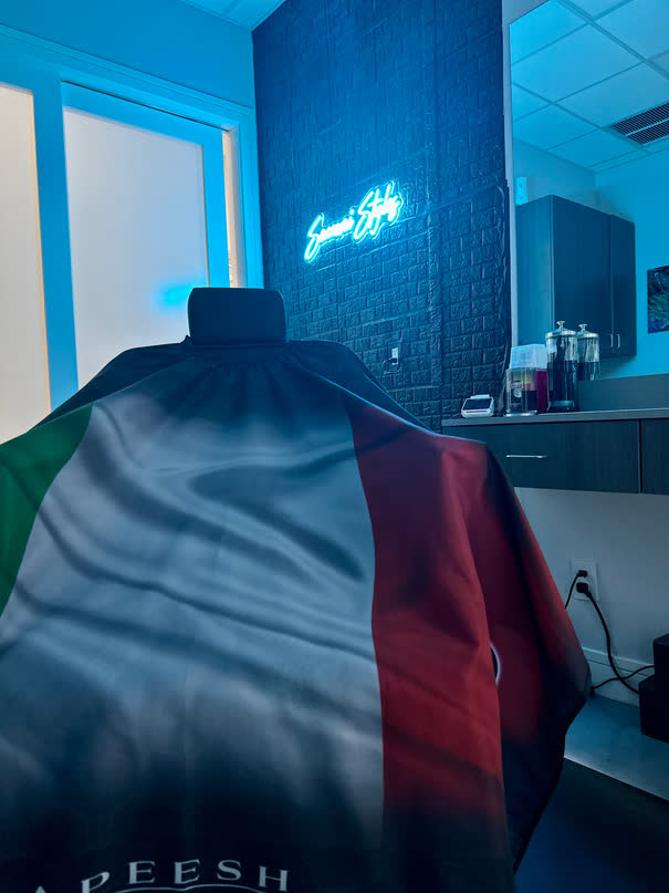 The barber chair inside Suite 102 with the Sacconi Styles sign glowing on the black brick wall